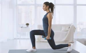 woman doing lunges with dumbbells at home