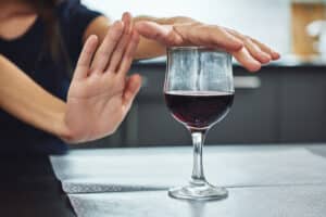 woman declining a glass of wine to maintain sobriety