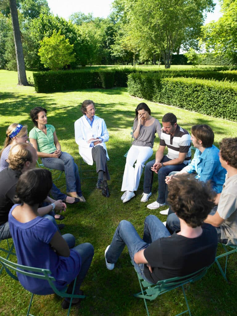 Circle of people in rehab outdoors The Bluffs Addiction Campuses