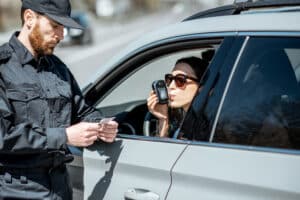 Policeman checking woman driver for alcohol intoxication The Bluffs Addiction Campuses