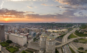 Aerial view of downtown district of Cincinnati city in Ohio, USA at sunset. Brightly illuminated high skyscraper buildings in modern American midtown.